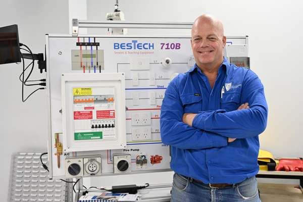 Man in blue shirt next to electrical training device