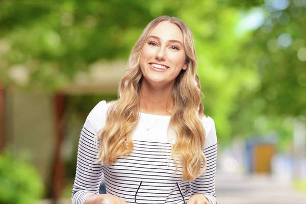 Beatrix King smiling holding her glasses