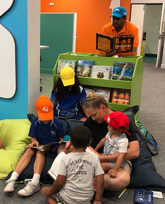 Woman with child on her lap and reading to children.