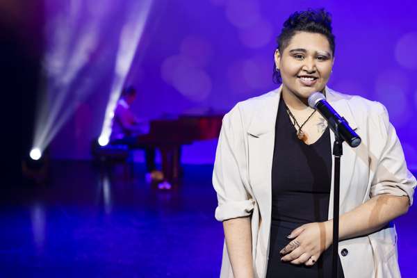 Chloe Pitt standing on stage with a microphone smiling