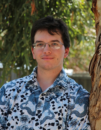 Christopher Lowe smiling against a tree