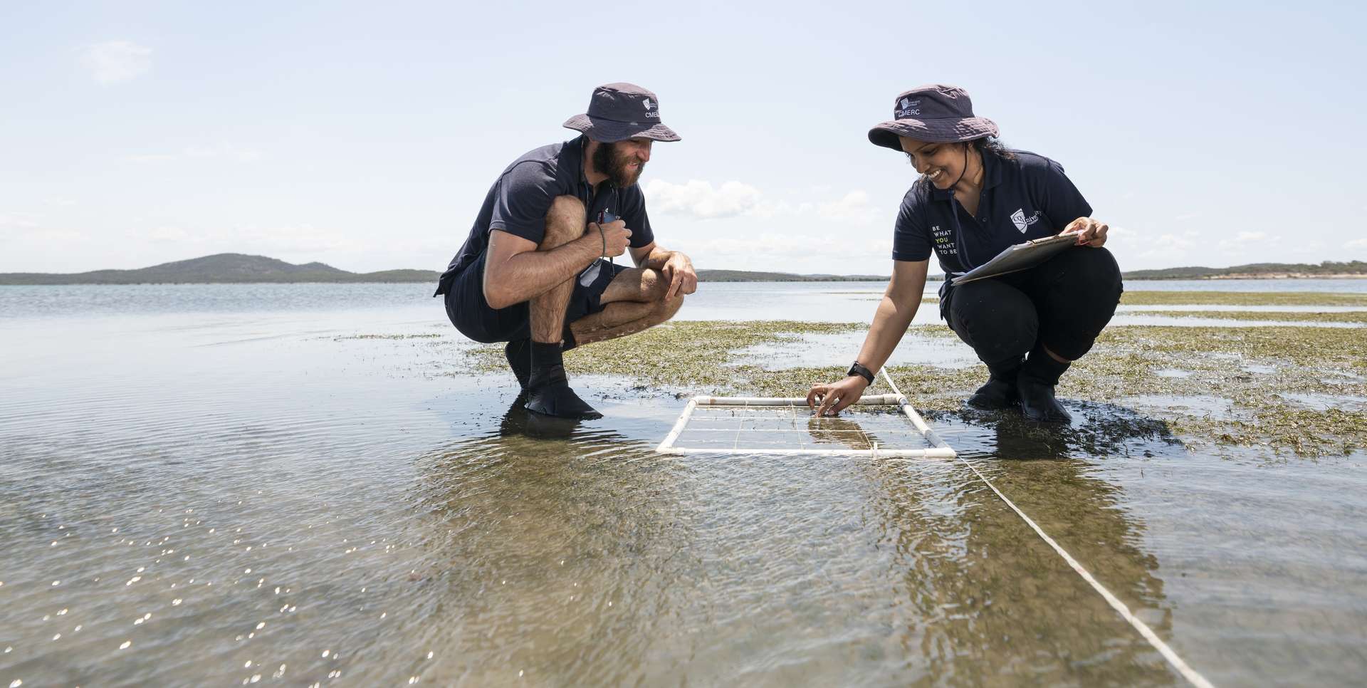 Two CMERC students squatting on a seagrass flat measuring its density