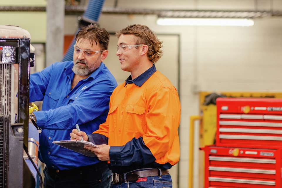 Apprentice working on machinery with a teacher
