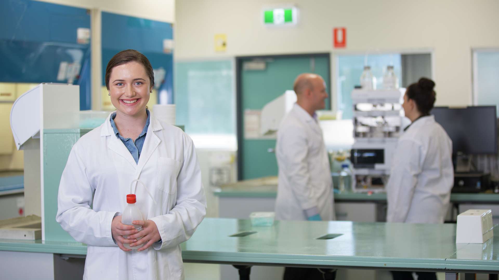 A medical science student smiling and holding a bottle in laboratory