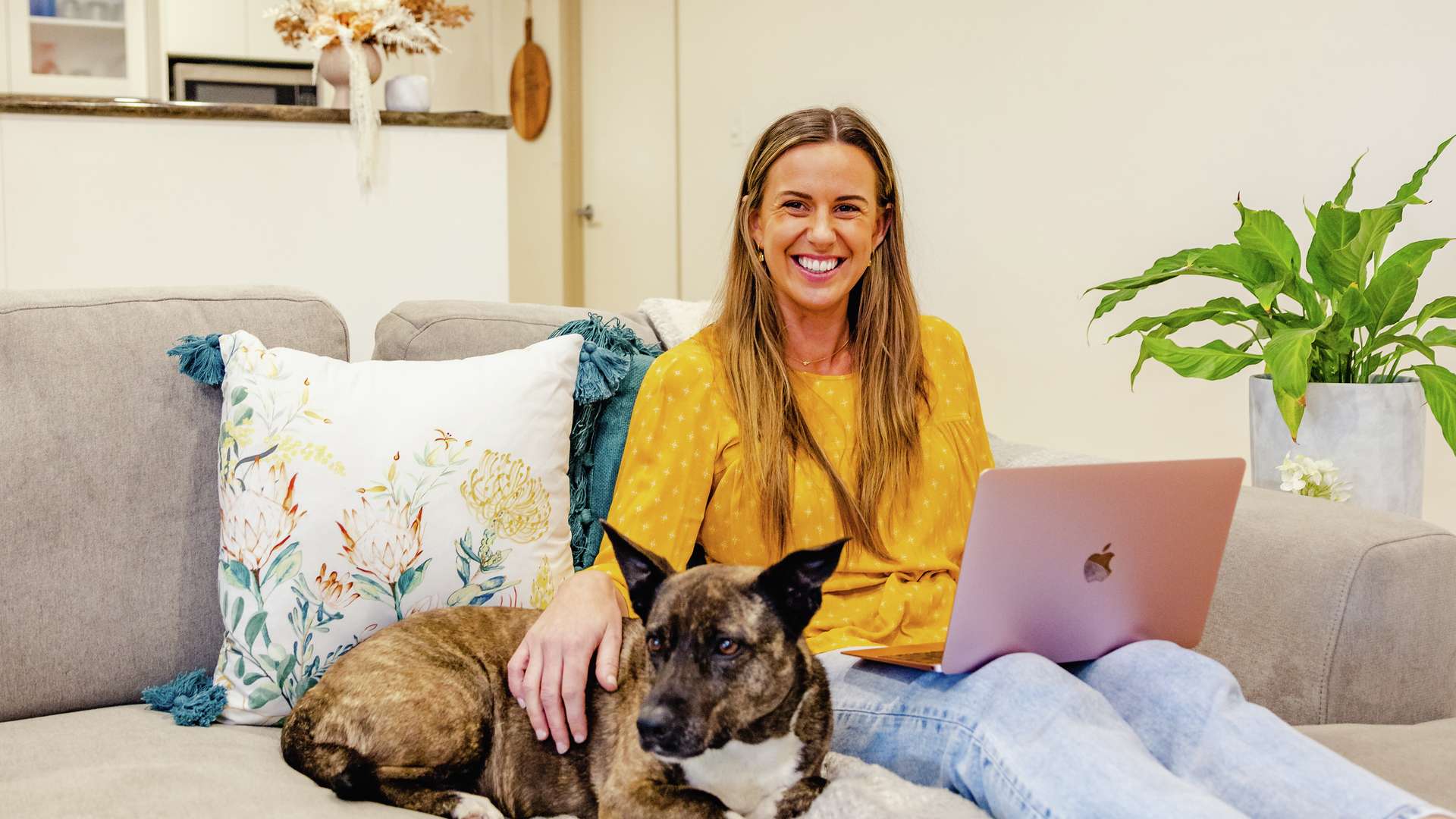 Person studying at home on laptop with dog on couch