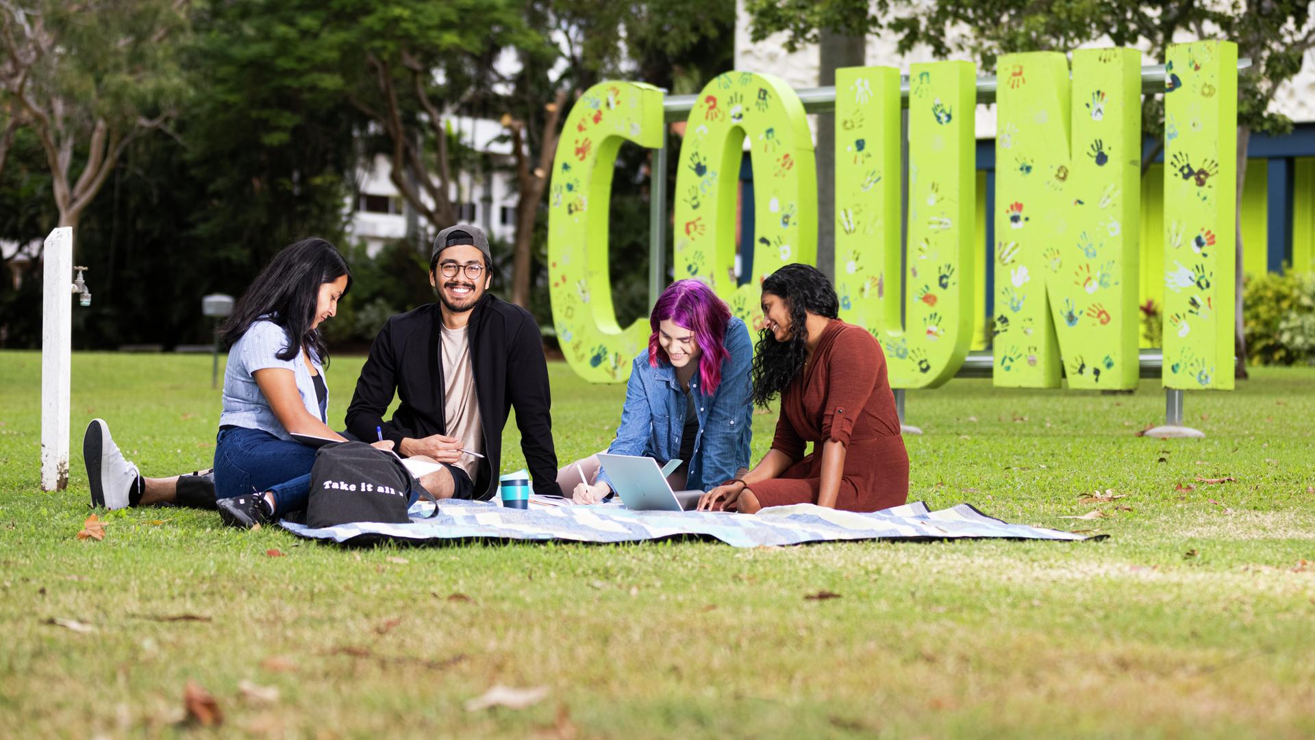 CQU students sitting on a blanket, on campus