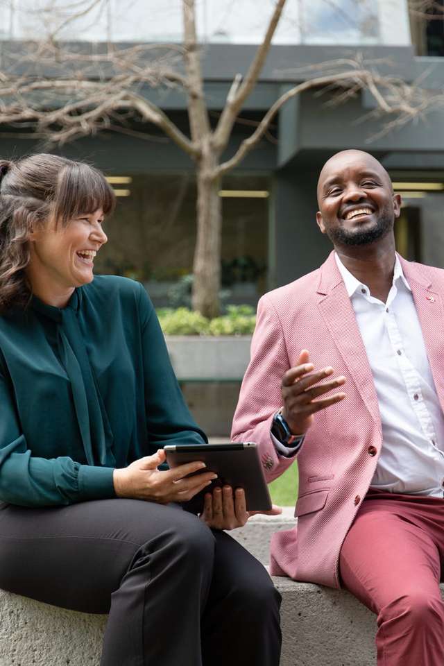 Two students sitting outdoors laughing.