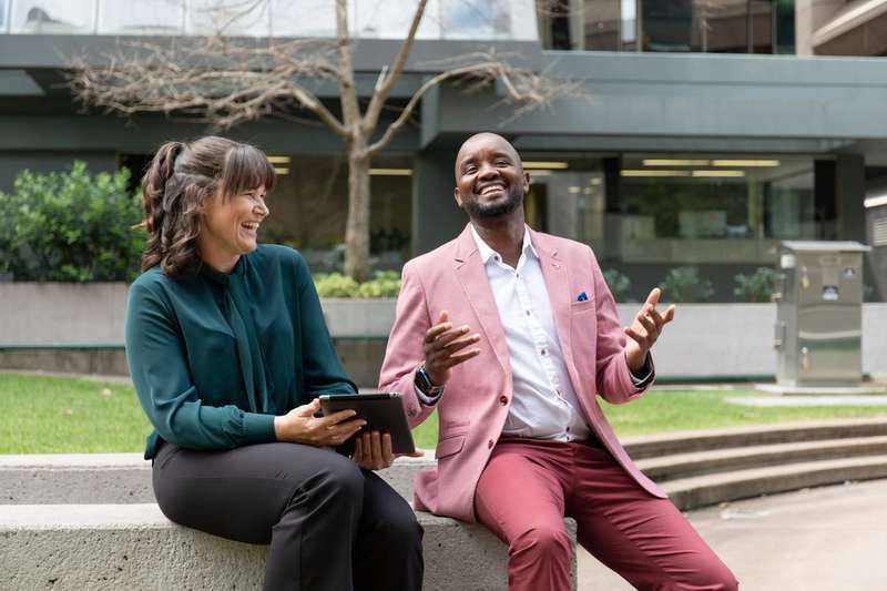 Two students sitting outdoors laughing.