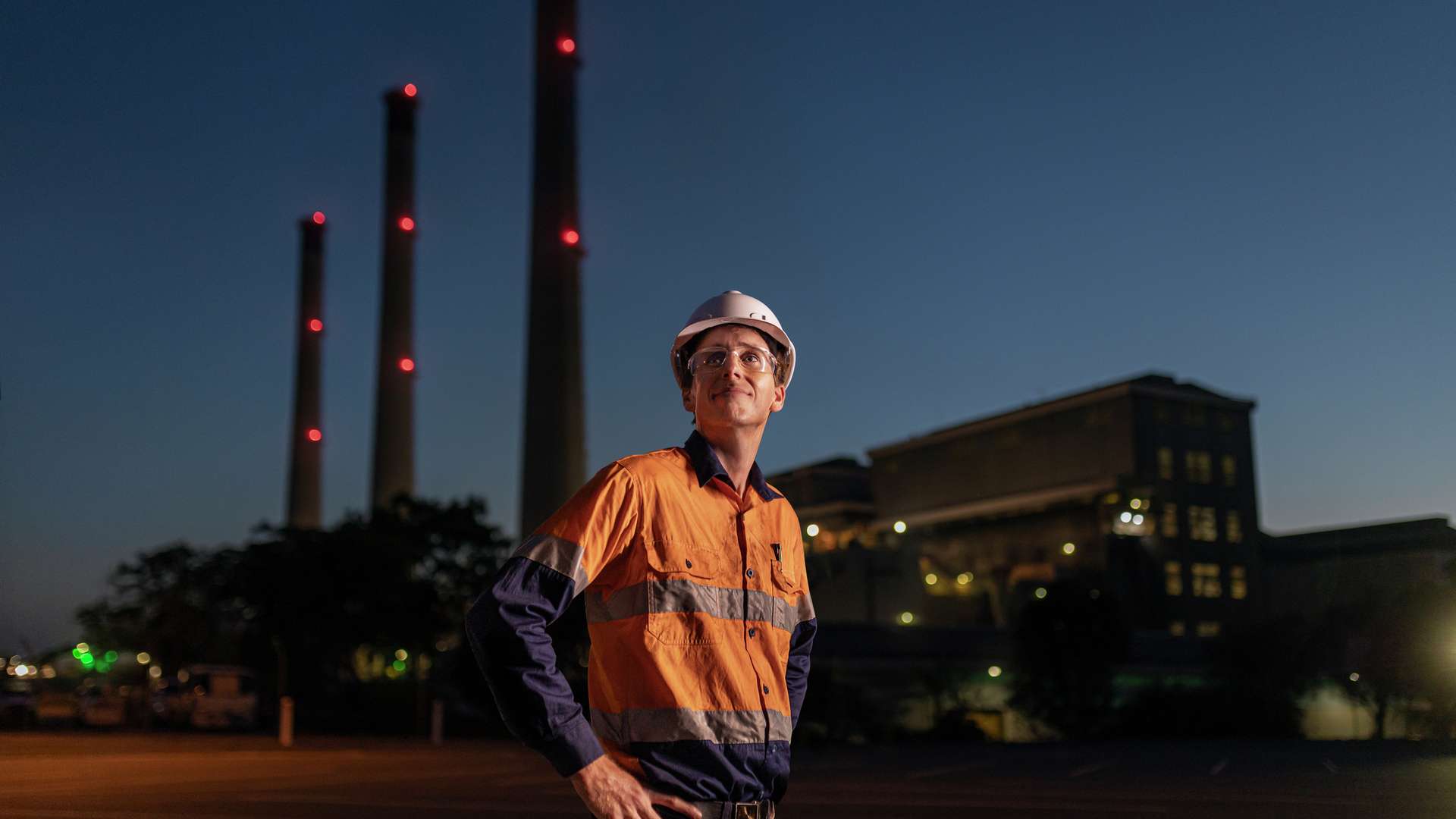 Mining student wearing PEE standing in front of a mine site at dusk