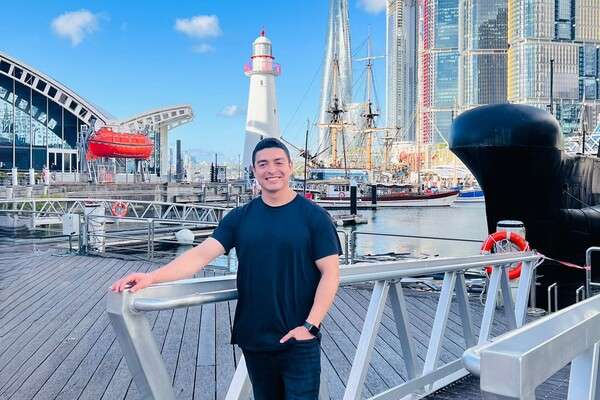 International student Diego Rodrigo Nieves Quiroz from Peru standing on a pier with one hand in jean pocket and smiling at the camera.