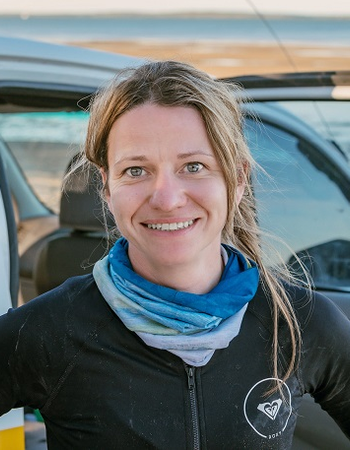 Elizabeth Andrews standing with her vehicle with the ocean in the background
