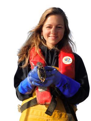 Emma Theobald in a life jacket holding a crab