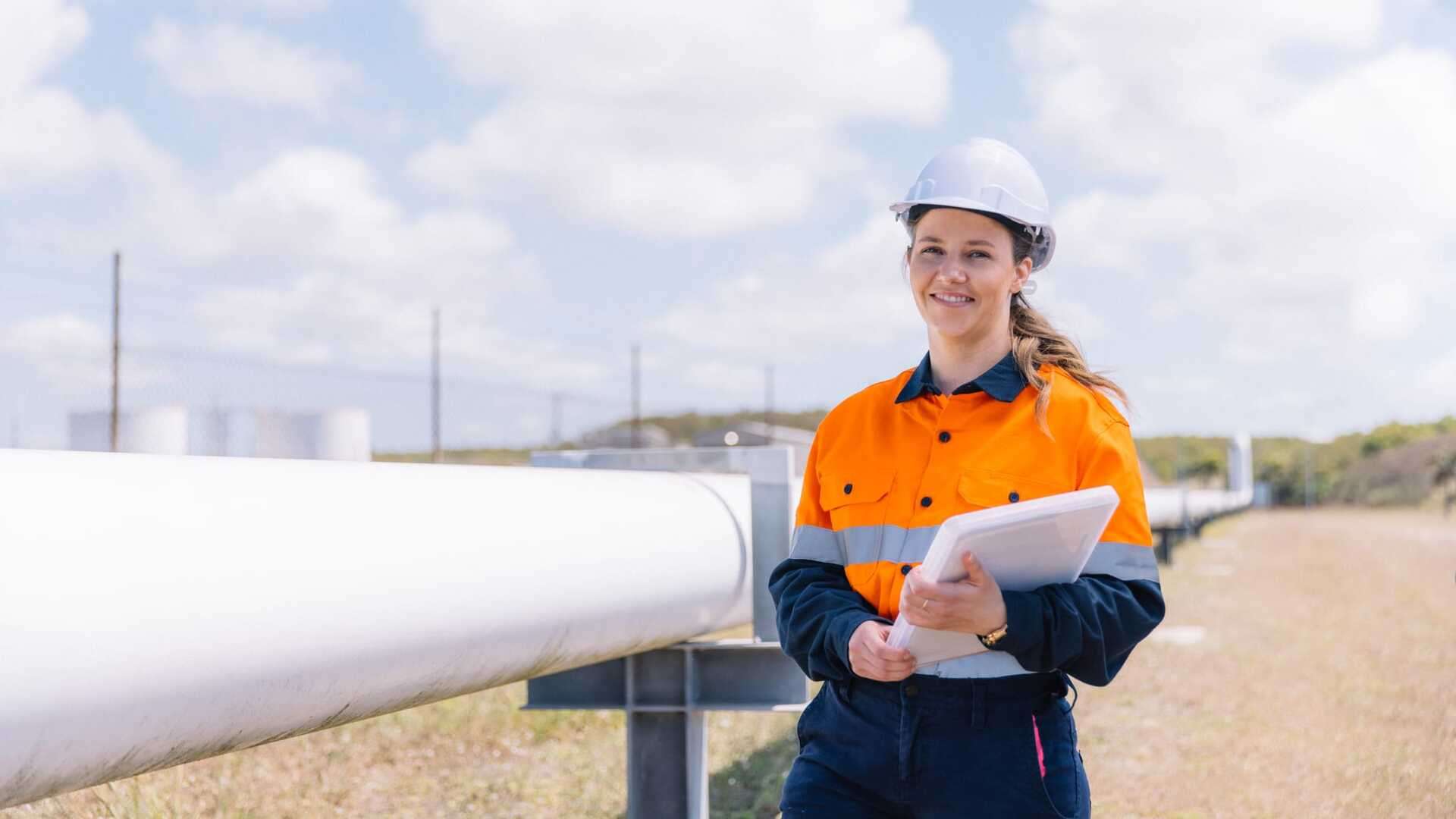 Engineering Cadet Student wearing PPE standing with a large piping structure