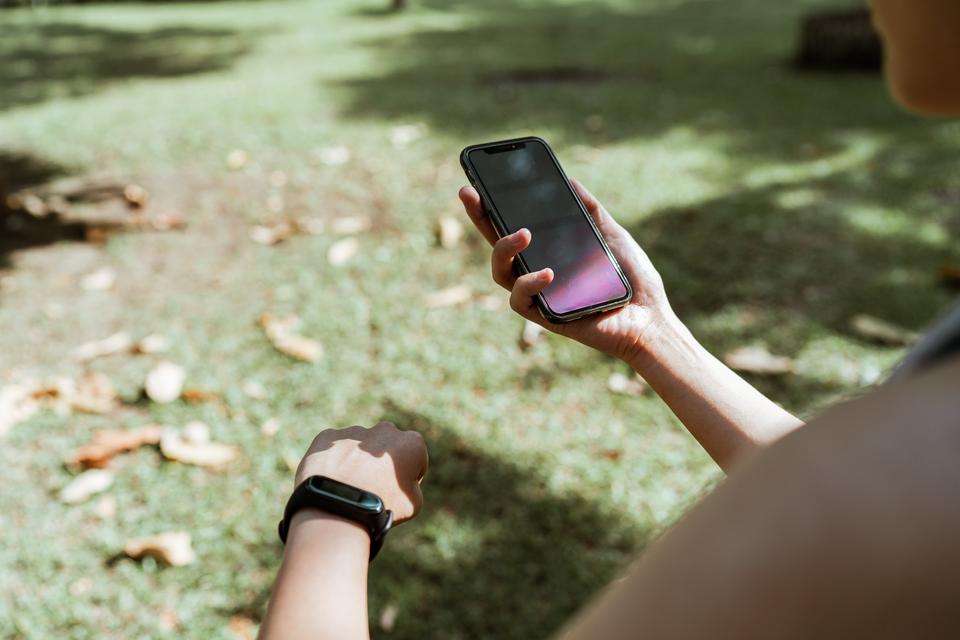 Person monitors fitness tracker using smartphone