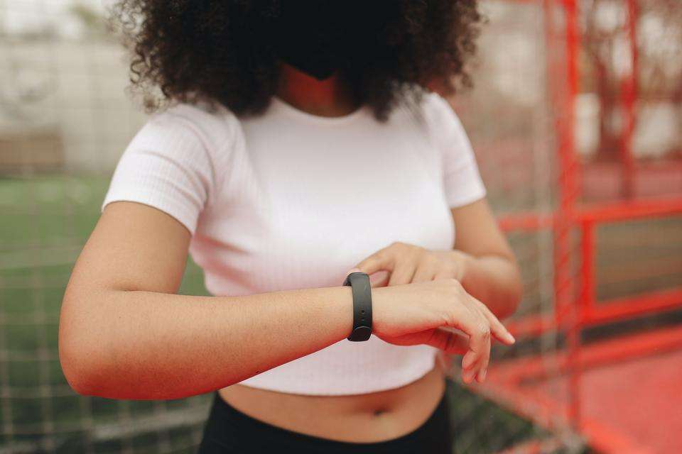 Person in activewear stands and monitors their fitness tracker