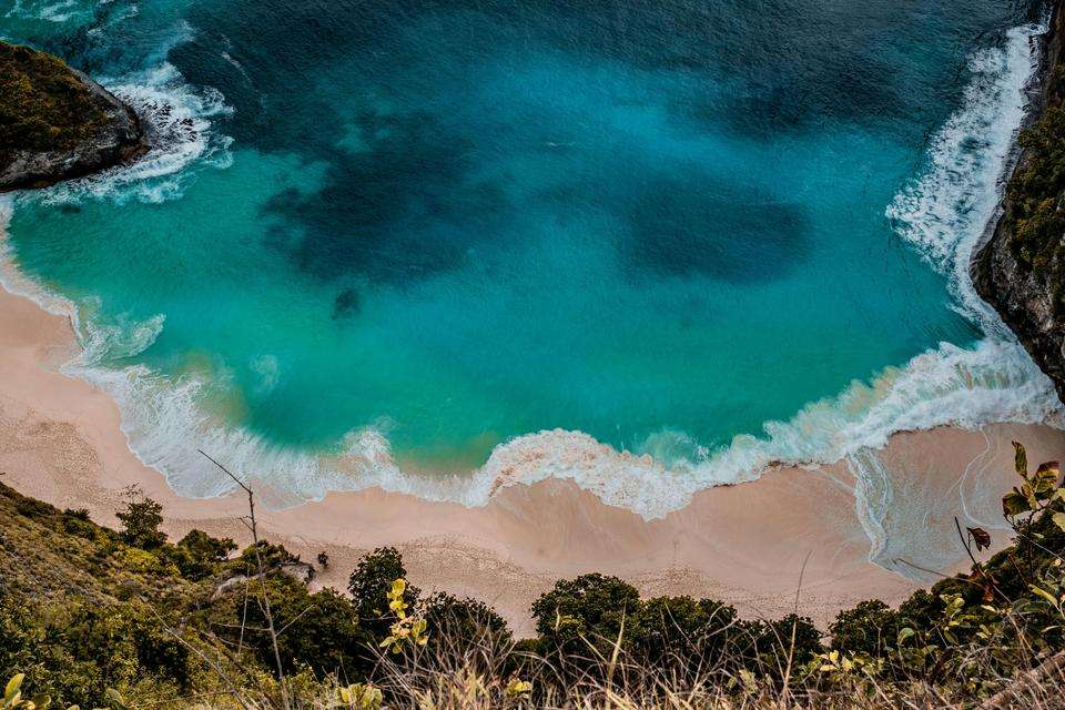 Bird's eye view of tropical island sea with surrounding scrub and cliff faces