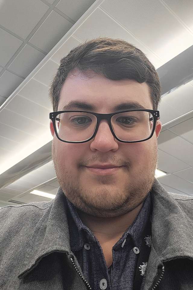 Smiling Nicholas Sorbello wearing black framed reading glasses