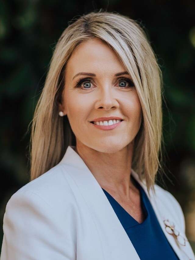 Tanya O'Shea smiling whilst wearing blue top and white suit coat