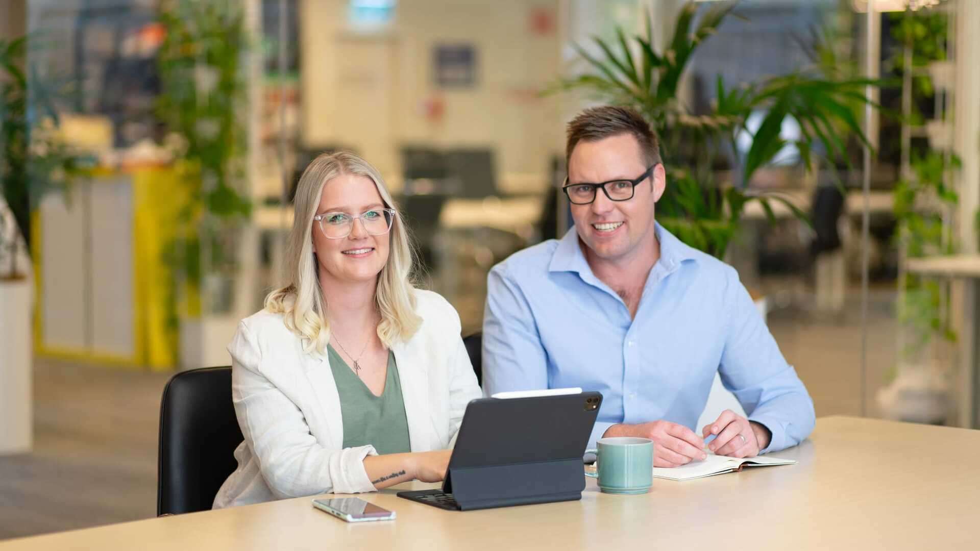 Two University academics working together in an open plan office on a laptop