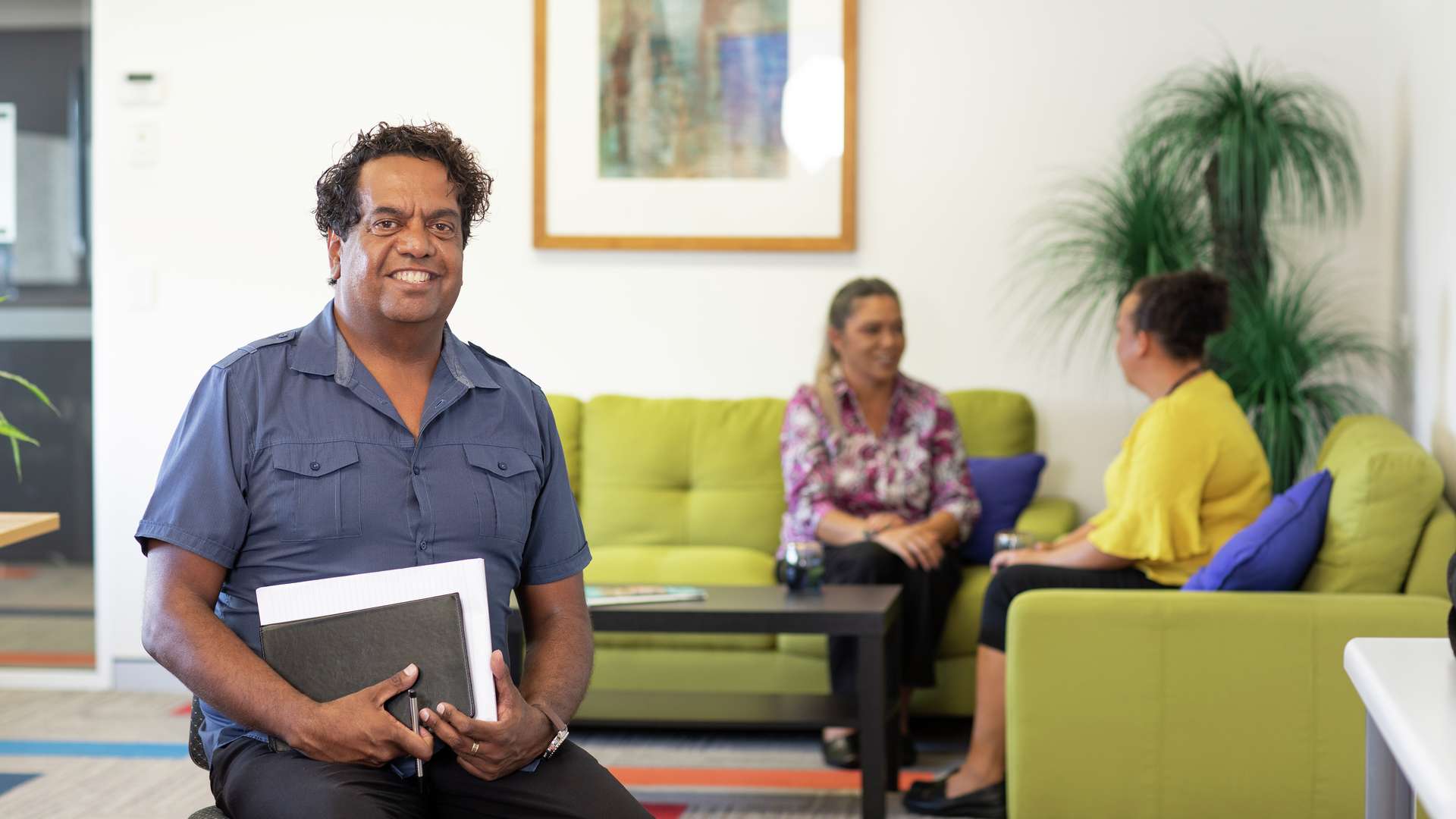 First Nations community service student sitting and smiling with other students chatting in the background