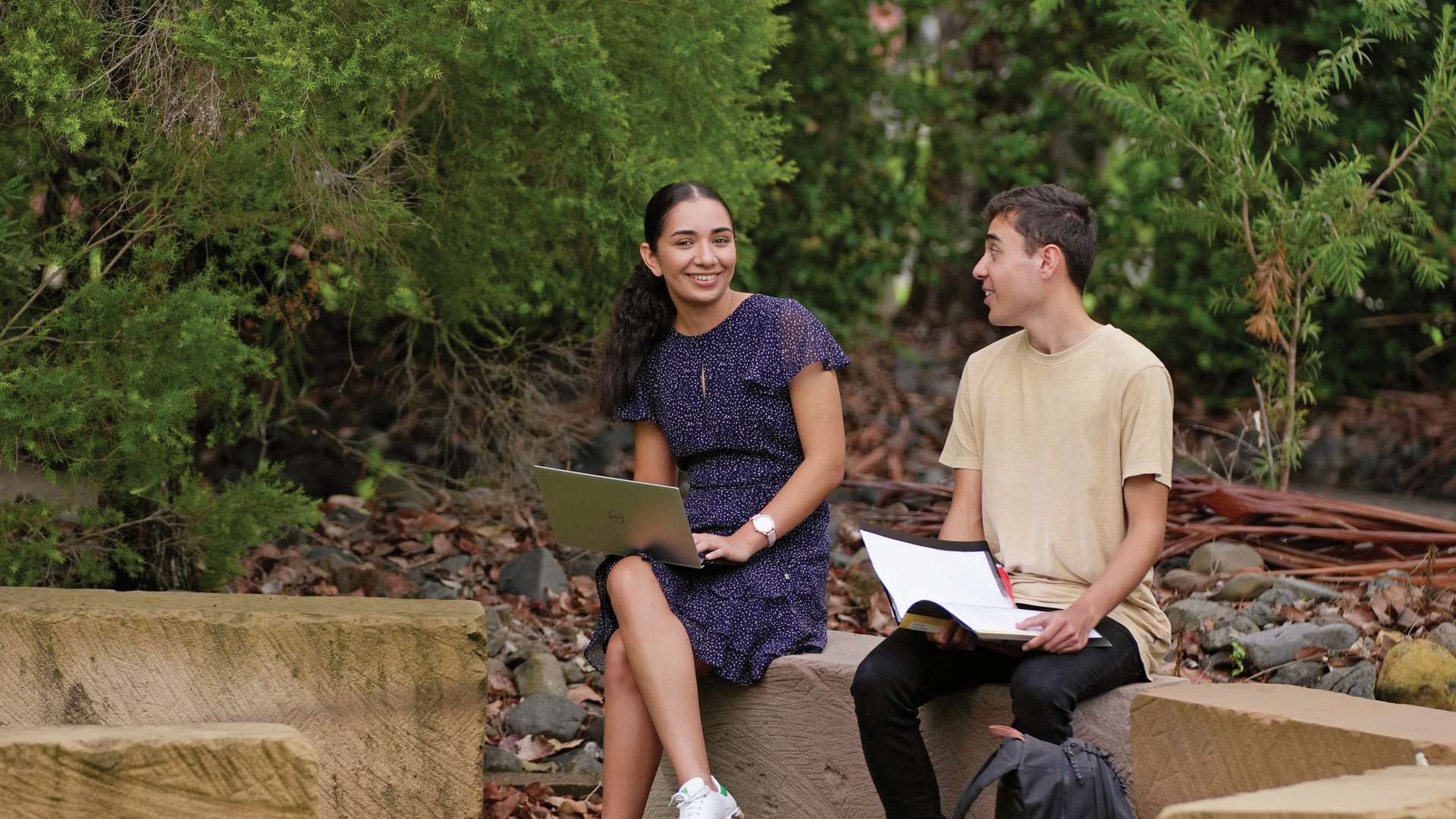 Two students sit in the yarning circle on CQU's Rockhampton campus and study together.