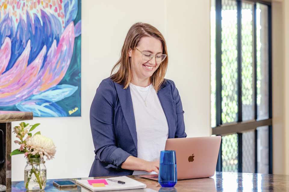 A mature age student typing on a laptop at a bench top at home