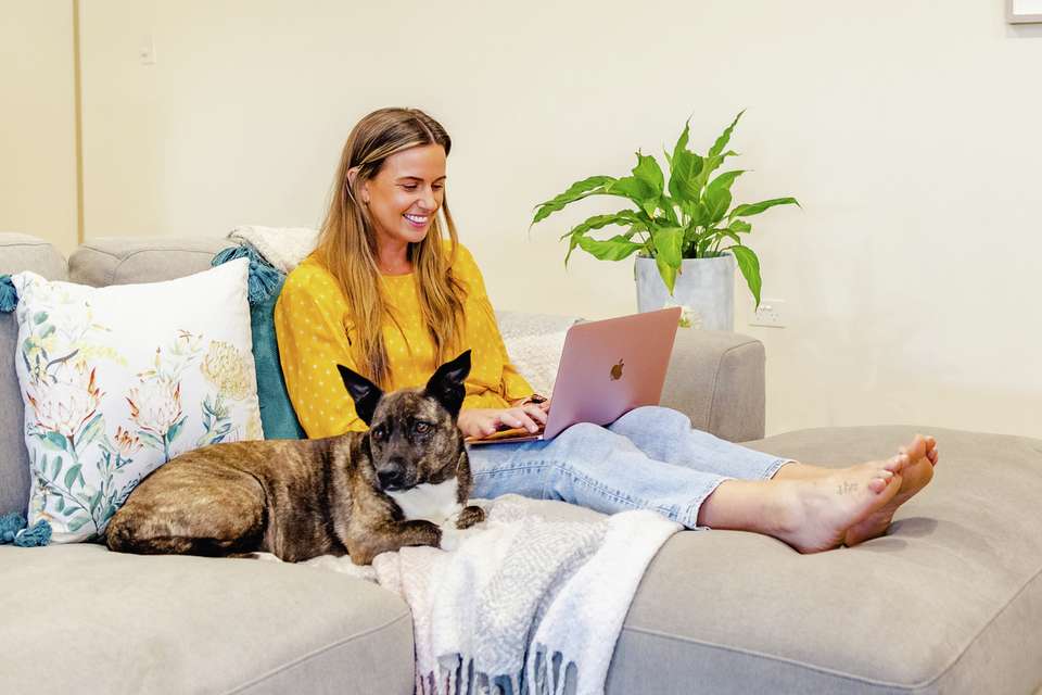 a student studying on the couch with their dog at home