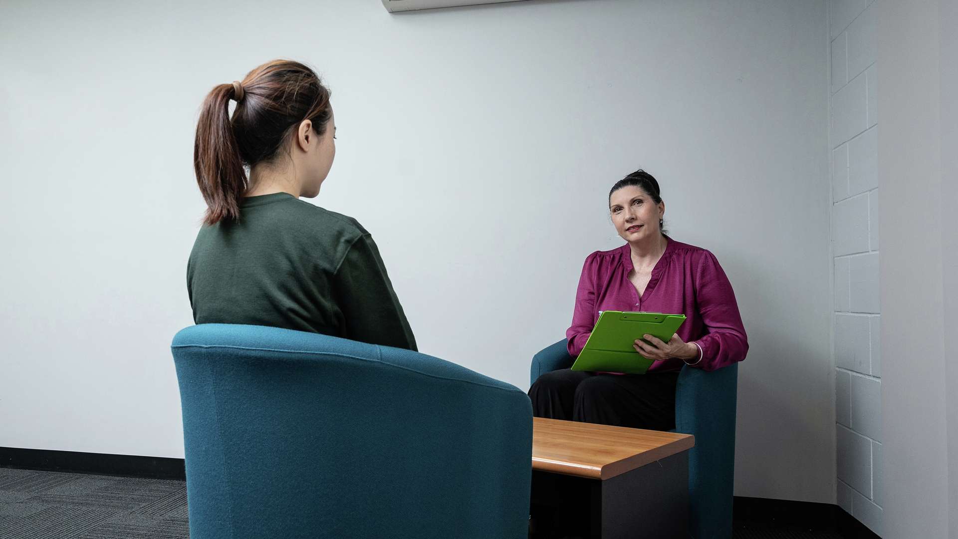 Two ladies seated in a room having a discussion.