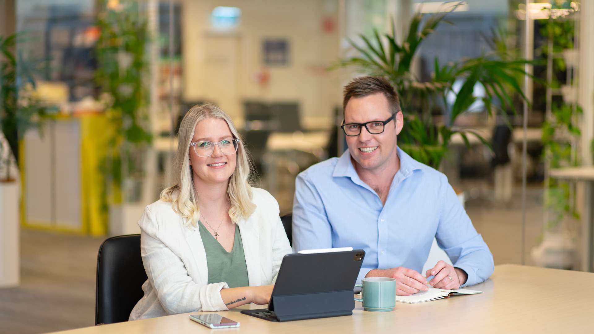 A male and female student smiling with a laptop open