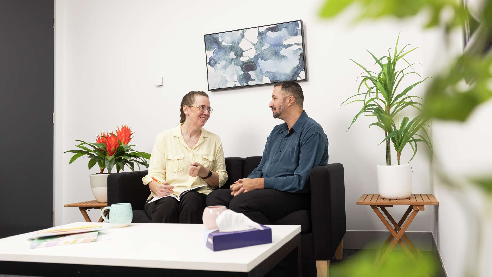 Counselling staff member talking with another staff member on a couch in a private room