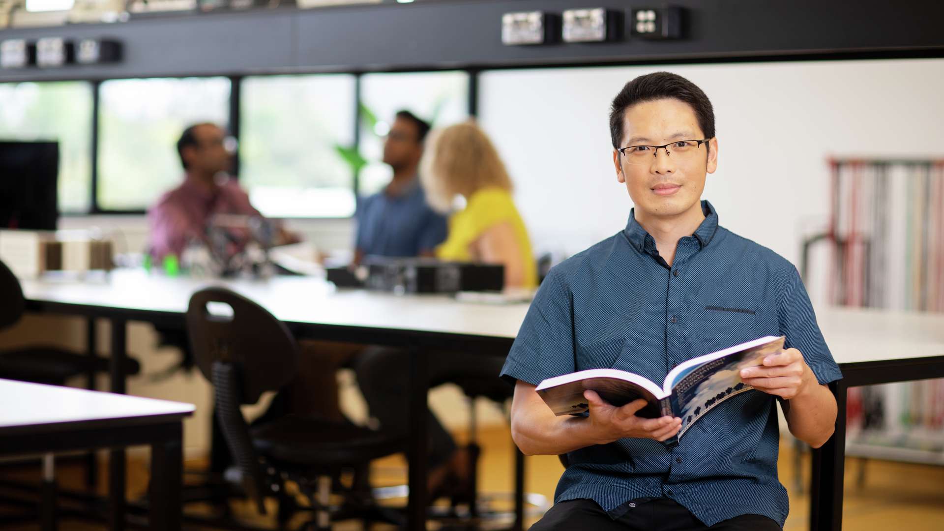 IT student holding an open textbook looking at the camera