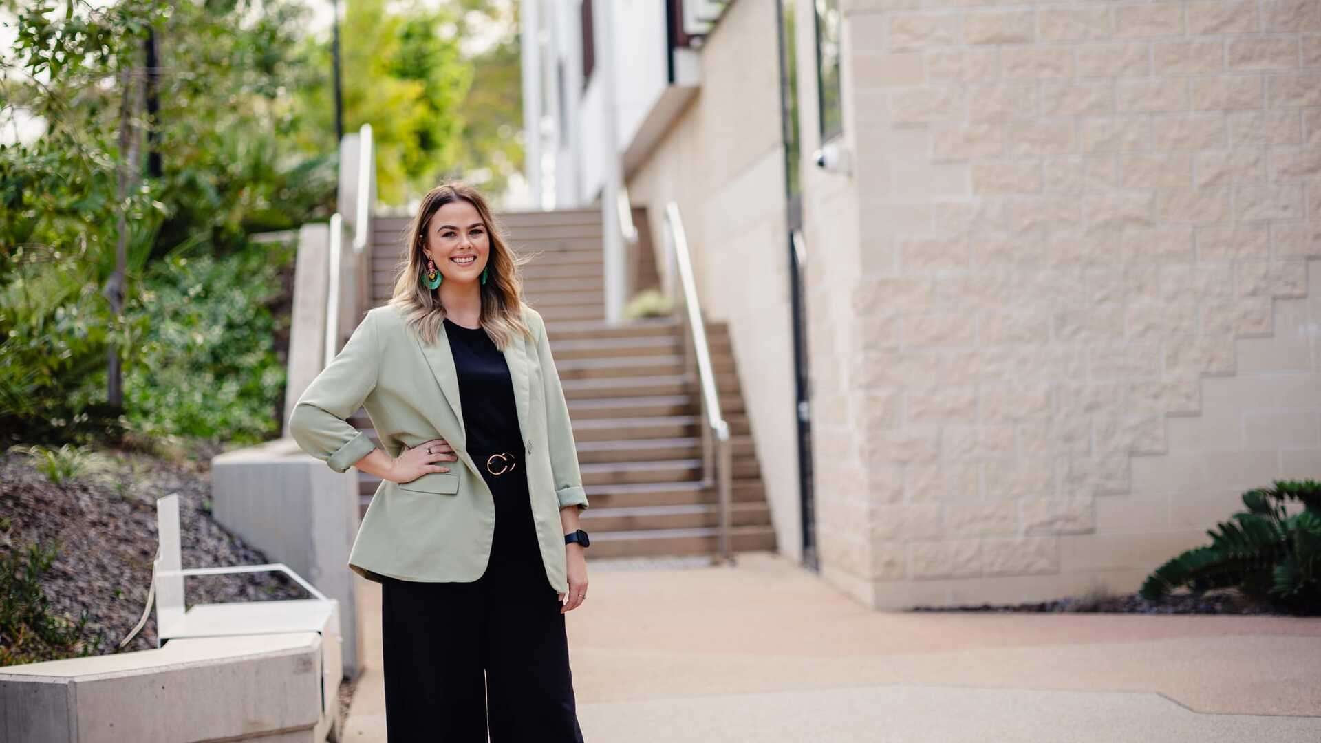 Woman smiling in front of stairs with hand on hip