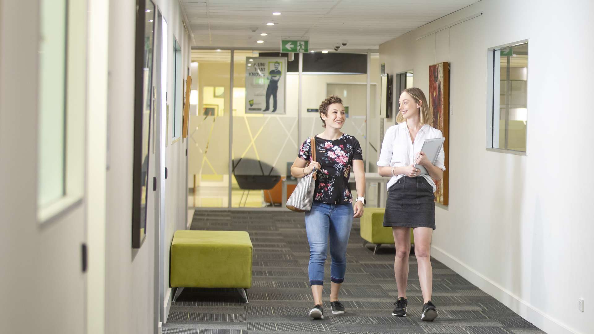 Two people walking down a corridor smiling