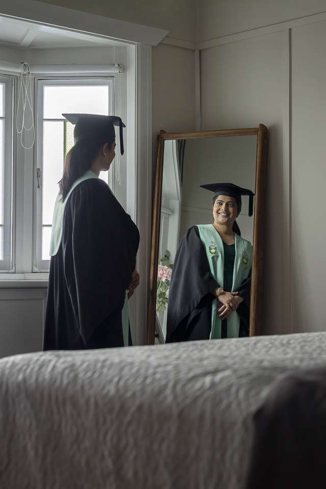 CQU graduate smiling and looking in mirror at reflection