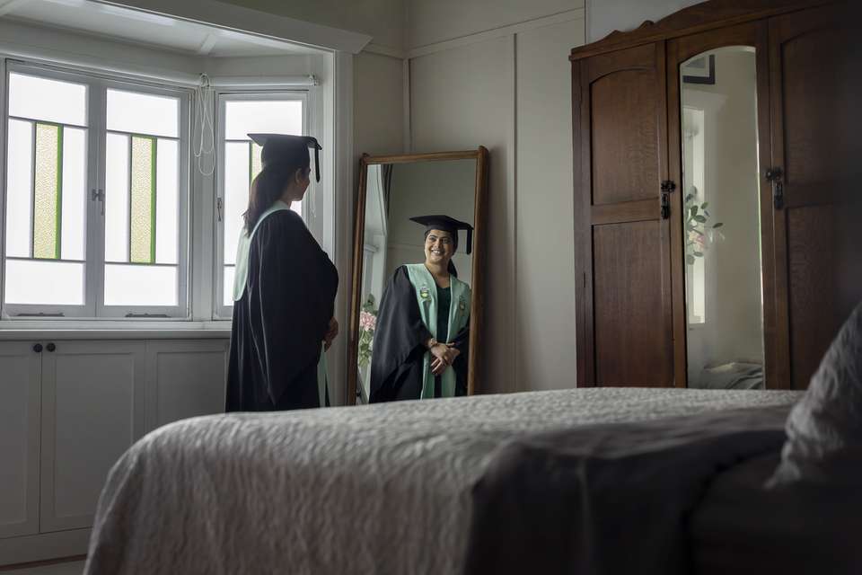 CQU graduate smiling and looking in mirror at reflection