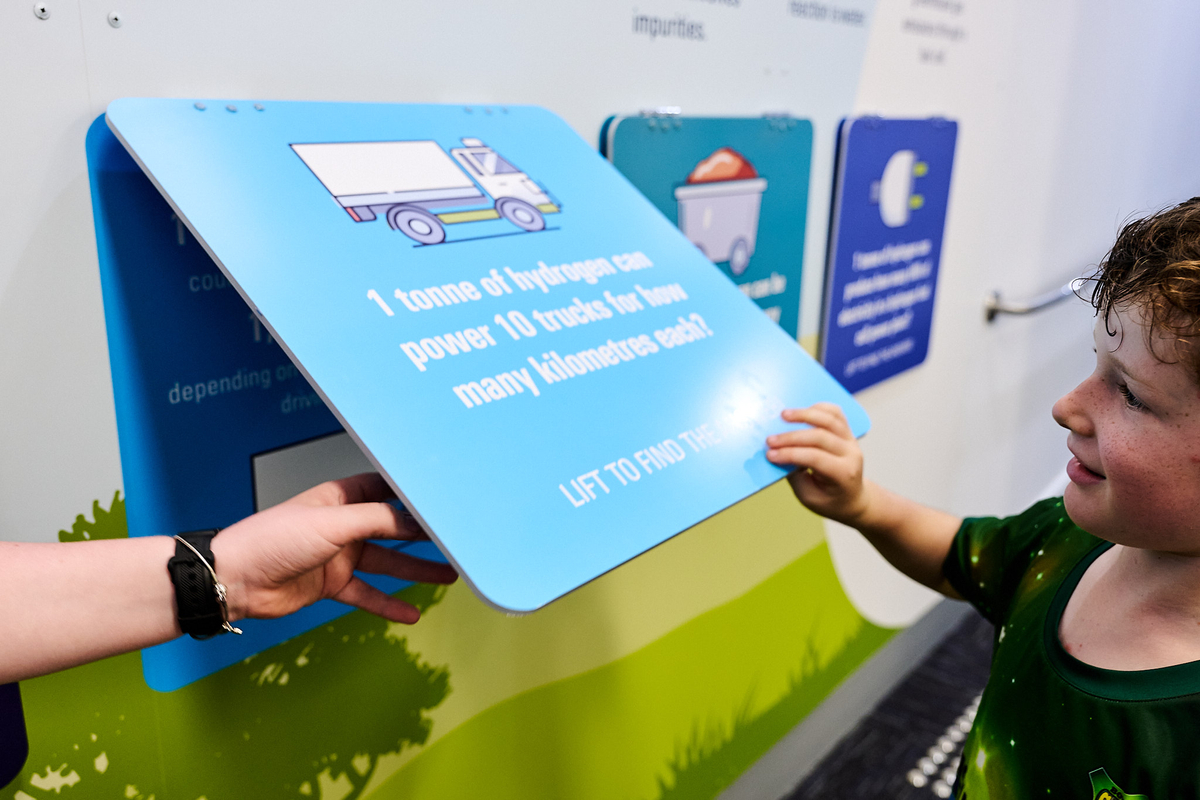Young boy turning over flip cards on Hydrogen Central wall to discover new facts about hydrogen