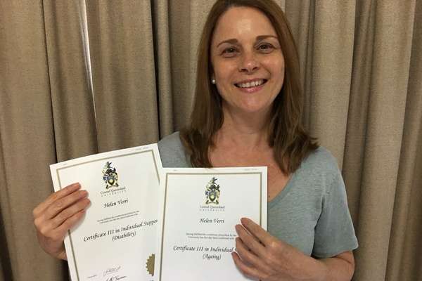 Helen Verri smiling holding two certificates In Individual Support