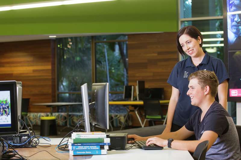 CQU staff member helps a student on a computer.