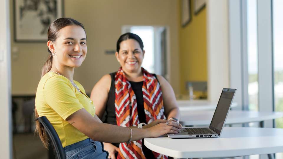 Student and tutor sitting at a table and smiling