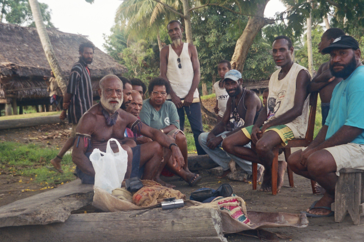 Group of people sitting and standing outdoors under trees