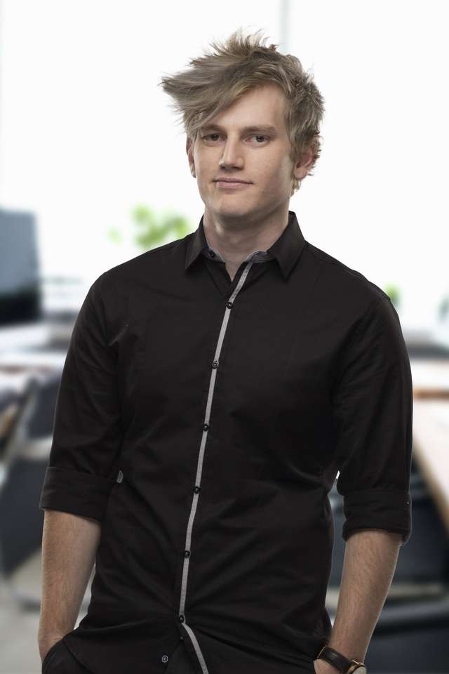 Isaac Jensen smiling with a bluer office in his background