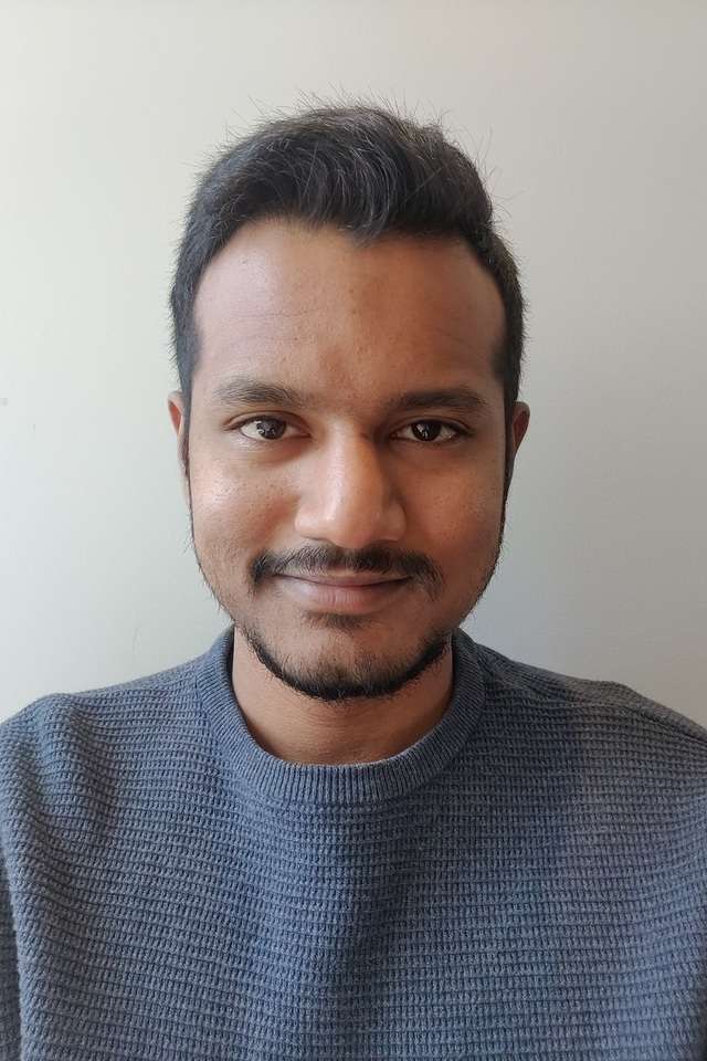 Jaswanth Valupadasu smiling with a grey background