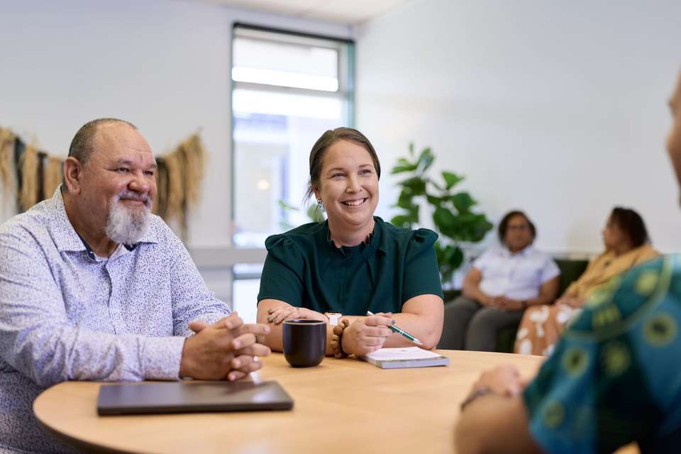 People sit around a table in a meeting room, engaged in conversation