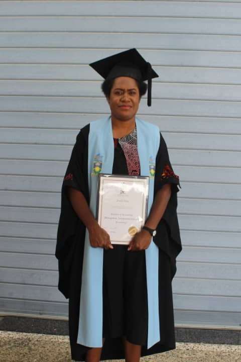 Jerusa Tilau at graduation in regalia holding the graduation certificate
