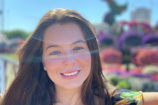 International student Julia Macedo Cesarano da Rocha from Brazil smiling at the camera with on arm leaning against a gate.