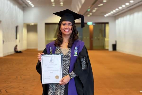 International student in graduation regalia with certificate in Melbourne.