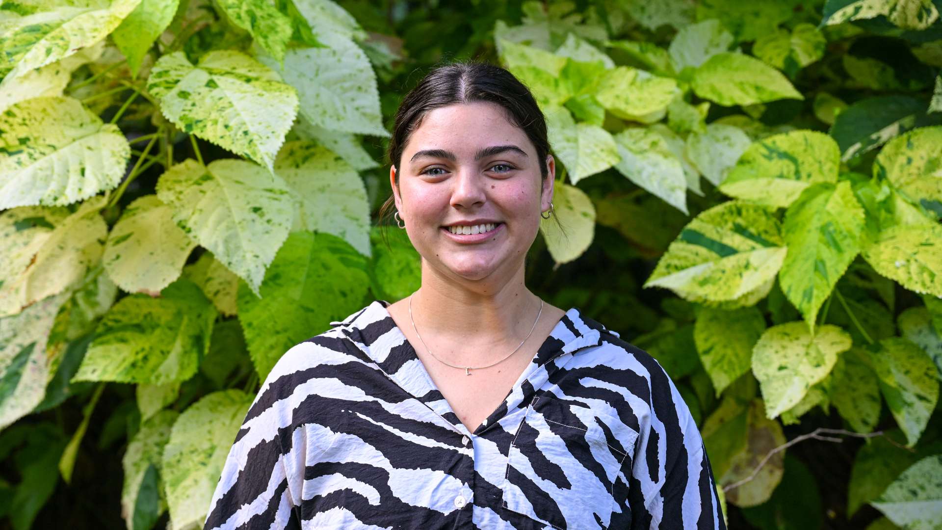Lainey Wilson smiling and standing in front of greenery