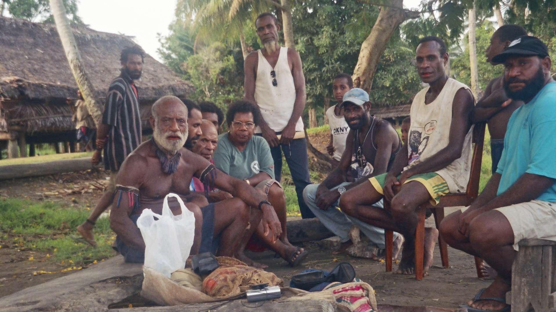 Group of people sitting and standing outdoors under trees