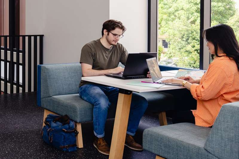 CQU students study together at tables in an open plan area on campus.