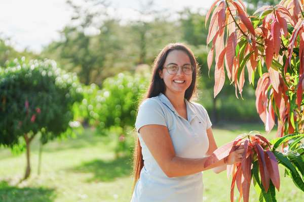 Maisa Pereira outdoors standing next a tree holding its leaves